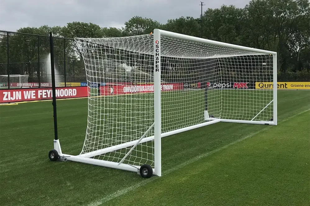 Ein weißes Fußballtor mit hinteren Spannstangen und Rädern auf Fußballplatz Ein weißes Fußballtor mit hinteren Spannstangen und Rädern auf Fußballplatz